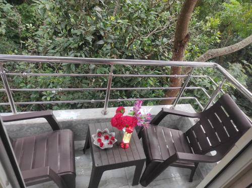 a balcony with two chairs and a table with flowers at Sharma Jee Farm House Yercaud in Yercaud