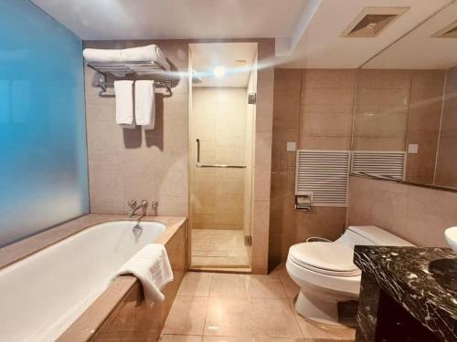 a bathroom with a tub and a toilet and a sink at Chateau Lizhi Hotel in Beijing