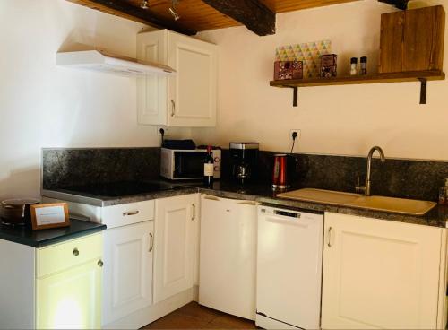 une cuisine avec des armoires blanches et des comptoirs noirs dans l'établissement Au coeur de l'un des plus beaux villages de France, à Beynac-et-Cazenac