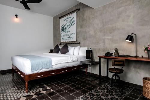 a hotel room with a bed and a desk with avertisement at Aquarius Hotel and Urban Resort in Phnom Penh