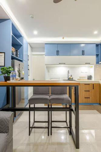 a kitchen with blue cabinets and a table with chairs at Balai ni Boss - Cozy Modern 1BR in Victoria Sports Tower in Manila