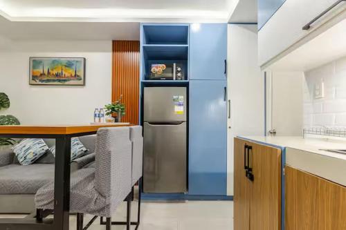 a kitchen with a table and a stainless steel refrigerator at Balai ni Boss - Cozy Modern 1BR in Victoria Sports Tower in Manila