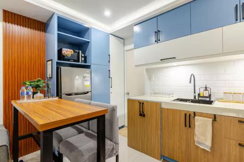 a kitchen with a wooden table and blue cabinets at Balai ni Boss - Cozy Modern 1BR in Victoria Sports Tower in Manila