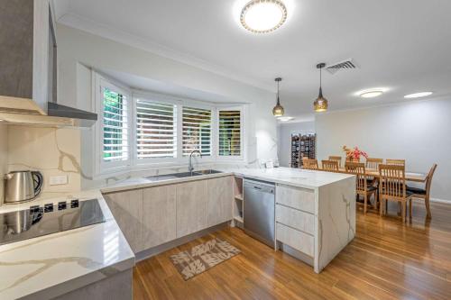 a kitchen with white counters and a dining room at Whisper on the Falls in Wentworth Falls