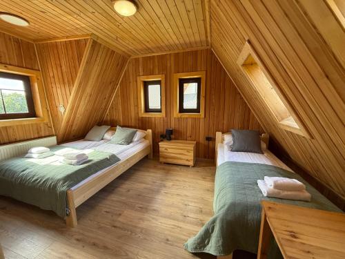 a bedroom with two beds in a wooden cabin at Łobrotno Gaździna - góralska chałupa na wyłaczność in Bukowina Tatrzańska