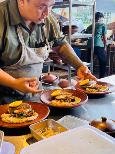 a person preparing food on a counter with plates of food at Green Lander Ubud in Ubud
