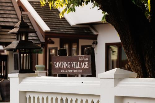a sign on a white fence in front of a house at Rimping Village in Chiang Mai