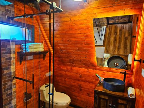 a bathroom with a toilet and a wooden wall at Glamping Hakuna Matata in Monguí