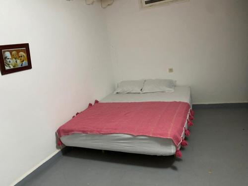 Cama en habitación blanca con manta roja en اوناغة الصويرة, en Essaouira
