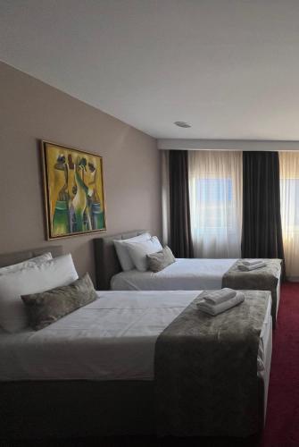 a hotel room with two beds and two ottomans at Garden City Hotel Konjic in Konjic
