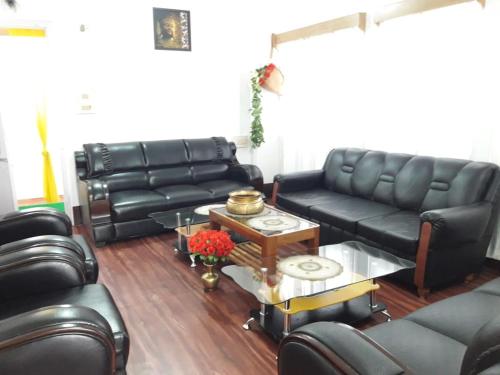 a living room with black leather couches and a table at Bliss Homestay in Tawang