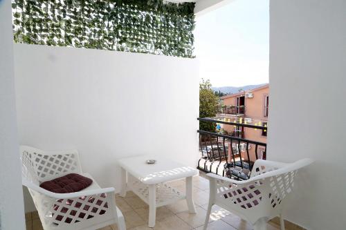 a balcony with two white chairs and a table at Apartments Stevo Nikočević in Bar