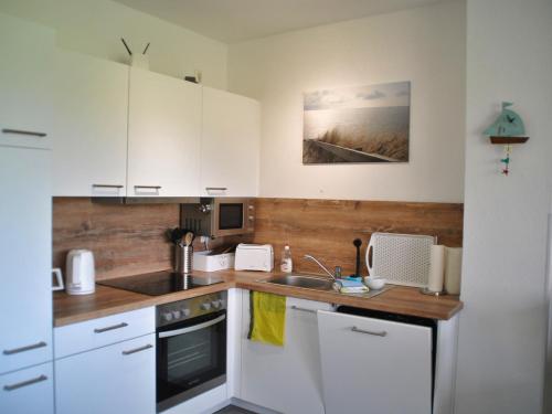 a kitchen with white cabinets and a sink at Kuschelnest - Tossens in Stick