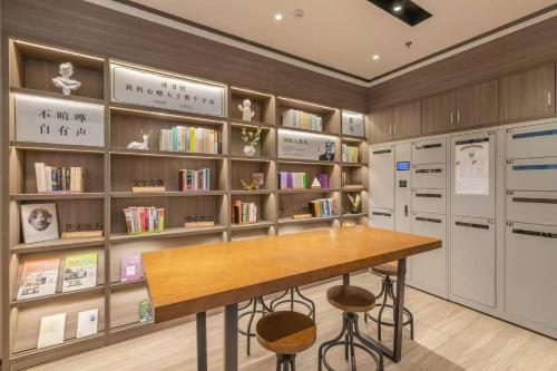 a library with a table and shelves of books at Hanting Hotel Beijing Temple of Heaven in Beijing