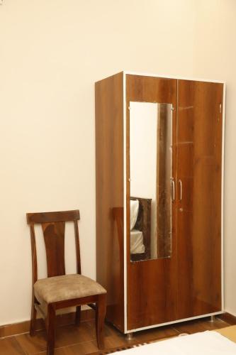 a wooden cabinet with a chair and a mirror at Pithoragarh Resort in Jodhpur