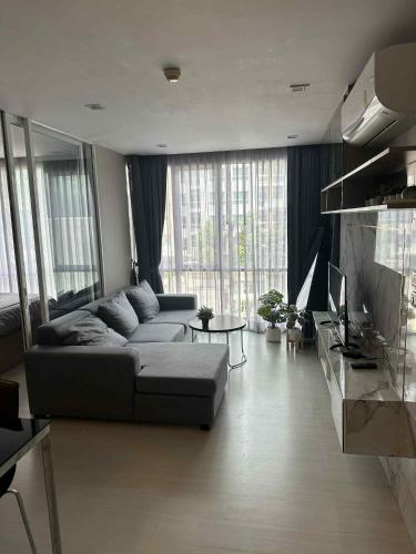 Una sala de estar con un sofá y algunas ventanas. en The Room Sukhumvit 64 Punnawithi, en Phra Khanong