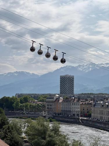 a group of ski lifts hanging over a river at Le Petit Perrière - HyperCentre - Quai de Grenoble in Grenoble