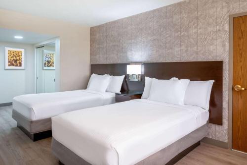 two beds in a hotel room with white pillows at Wyndham Indianapolis Airport in Indianapolis