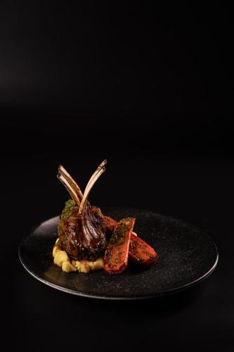 a black plate with a piece of meat and carrots at Radisson Dubai Damac Hills in Dubai
