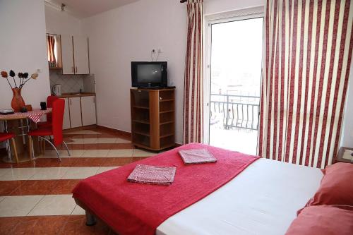 a bedroom with a bed with a red blanket and a television at Apartments Stevo Nikočević in Bar