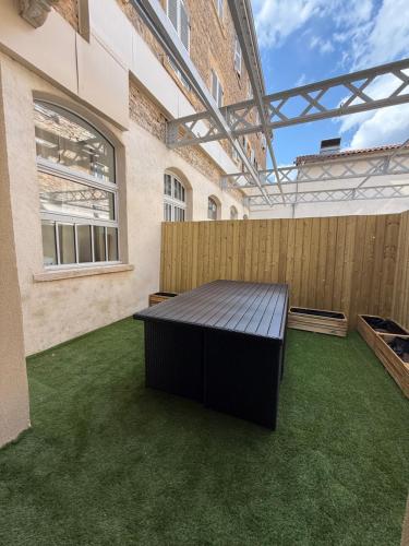 a patio with green grass and a wooden fence at La parenthèse in Villefranche-sur-Saône