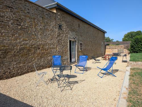 a group of blue chairs sitting next to a brick building at Dépendance du château de Remehan rénovée avec goût in Pouru-Saint-Rémy