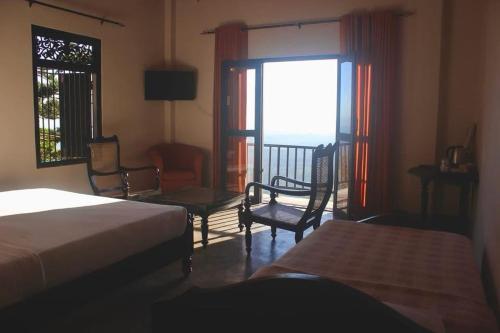 a bedroom with a bed and chairs and a window at Hotel SkyFall in Haputale