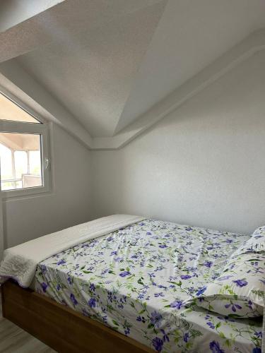 a bedroom with a bed with a floral comforter and a window at Lakeview Nest in Star Dojran