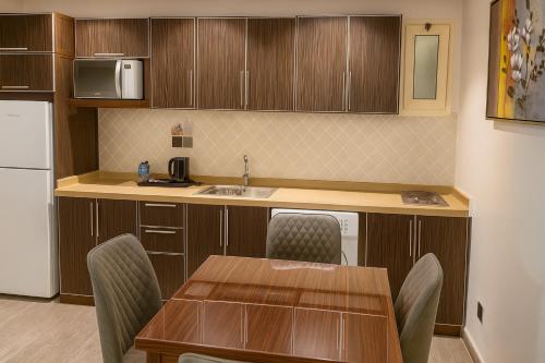 a kitchen with a table and chairs and a sink at Elite Served Apartments - Al Cornich in Jeddah