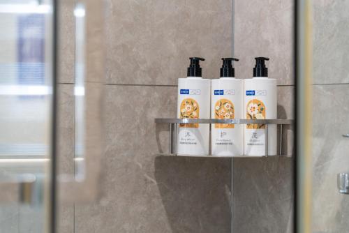 a group of four toiletries on a shelf in a bathroom at 来咖民宿酒店三亚市中心大悦城店 in Sanya