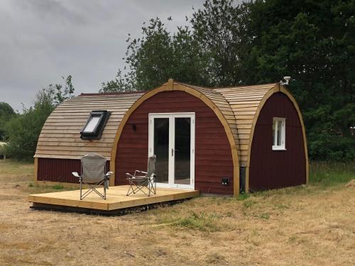 a small cabin with a porch and a chair on a deck at Muntjac Cabin in Elmswell
