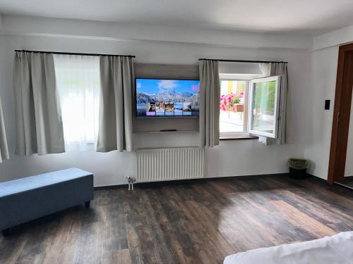a living room with a tv and two windows at Hotel Lainbach in Wängle in Reutte