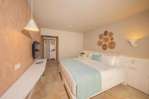 a bedroom with a large white bed and a television at Kairos Valley Wellness & Longevity in Datca