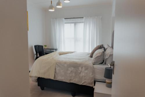 a white bedroom with a bed and a window at Chanty Serenity Apartment with Pool and Gym in Sandton