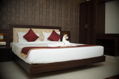 a bedroom with a large bed with red pillows at Rajathadri Palace Hotel Lake Breeze Suites in Bengaluru