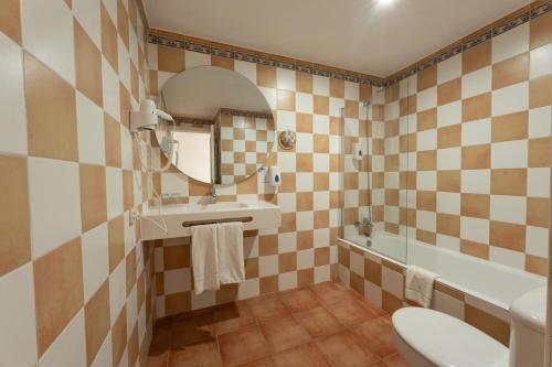 a bathroom with a sink and a toilet and a mirror at Hotel Club Es Talaial in Cala d´Or