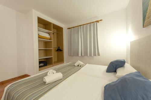 a bedroom with a large bed with two towels on it at Hotel Club Es Talaial in Cala d´Or