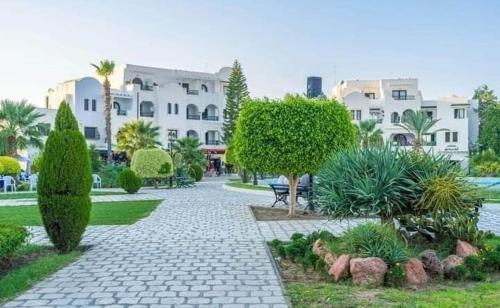 a stone walkway in a park with a building at Bungalow MARINA sousse KANTAOUI in Sousse