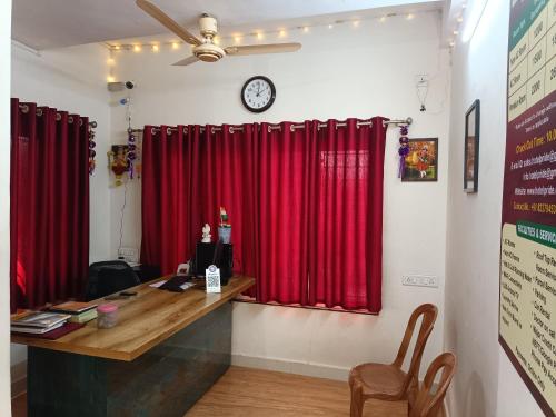 a room with red curtains and a desk with a clock at Pride Hotel in Ranjangaon