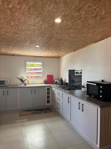 a kitchen with white cabinets and a black microwave at La KAZ Nout Racines in Saint-Leu