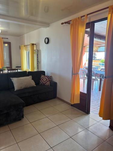 a living room with a couch and a sliding glass door at La KAZ Nout Racines in Saint-Leu