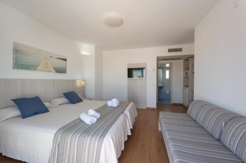 a bedroom with two beds with towels on them at Hotel Club Es Talaial in Cala d´Or
