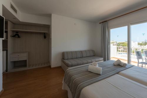 a bedroom with a large bed and a couch at Hotel Club Es Talaial in Cala d´Or