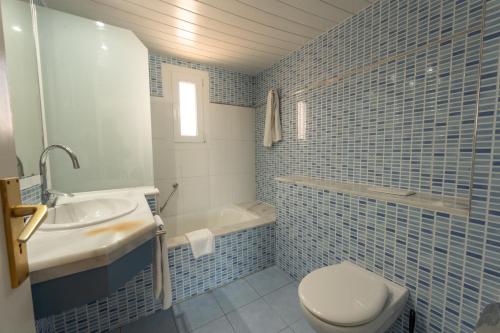 a blue tiled bathroom with a toilet and a sink at Hotel Club Es Talaial in Cala d´Or