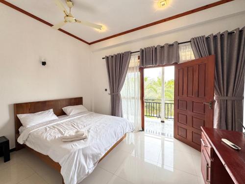 a bedroom with a bed and a large window at The Reef Resort in Nilaveli