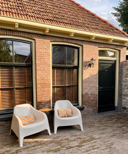 two white chairs sitting in front of a brick house at Stadslogement B&B Lytse Gysbert in Bolsward