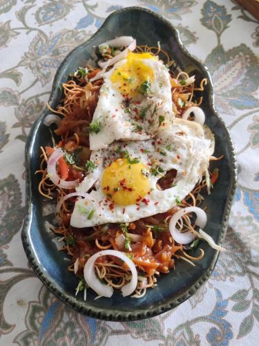 a plate of food with eggs on top of spaghetti at Seclude Ramgarh Taradale in Rāmgarh