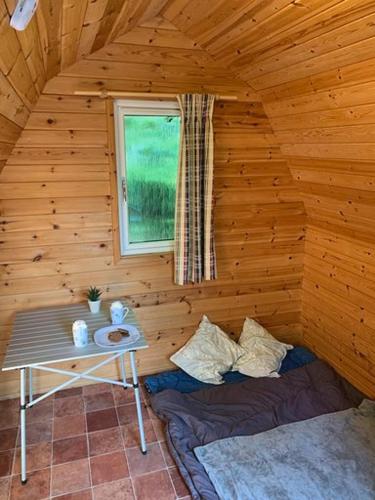 a room with a table and a bed in a log cabin at Woodland Camping Pod in Hale