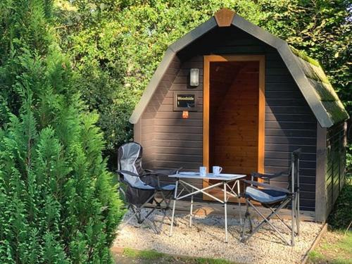 a small cabin with a table and chairs in front of it at Woodland Camping Pod in Hale