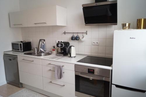 eine weiße Küche mit Spüle und Kühlschrank in der Unterkunft Apartment Old Town in Bolesławiec